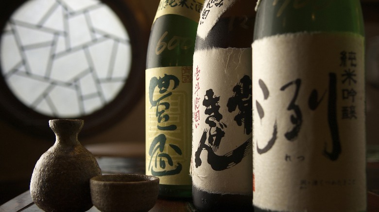 Three bottles of sake, with a small ceramic cup and serving bottle